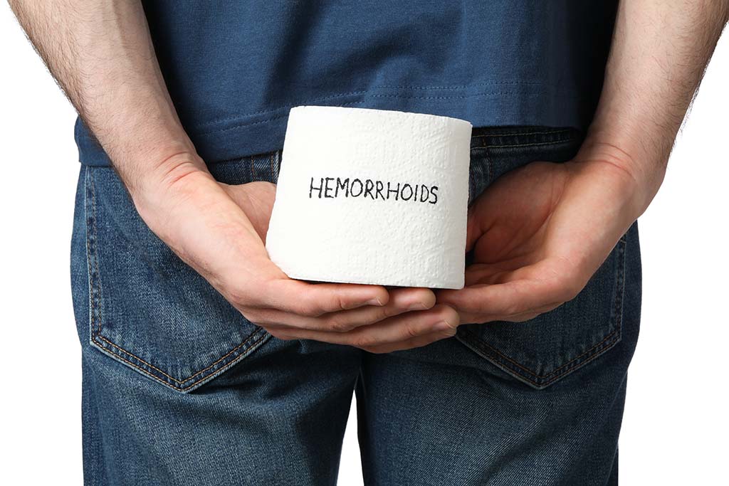 man holds toilet paper with inscription hemorrhoids, isolated on