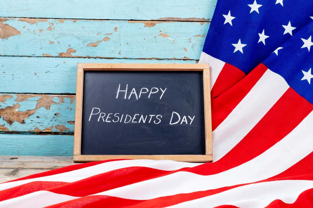 happy presidents day text on writing slate with america flag on blue wooden table with copy space. patriotism and identity, celebration.