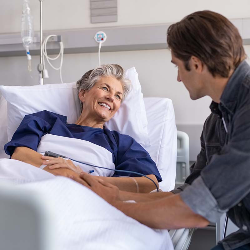 son visiting his smiling mother at hospital